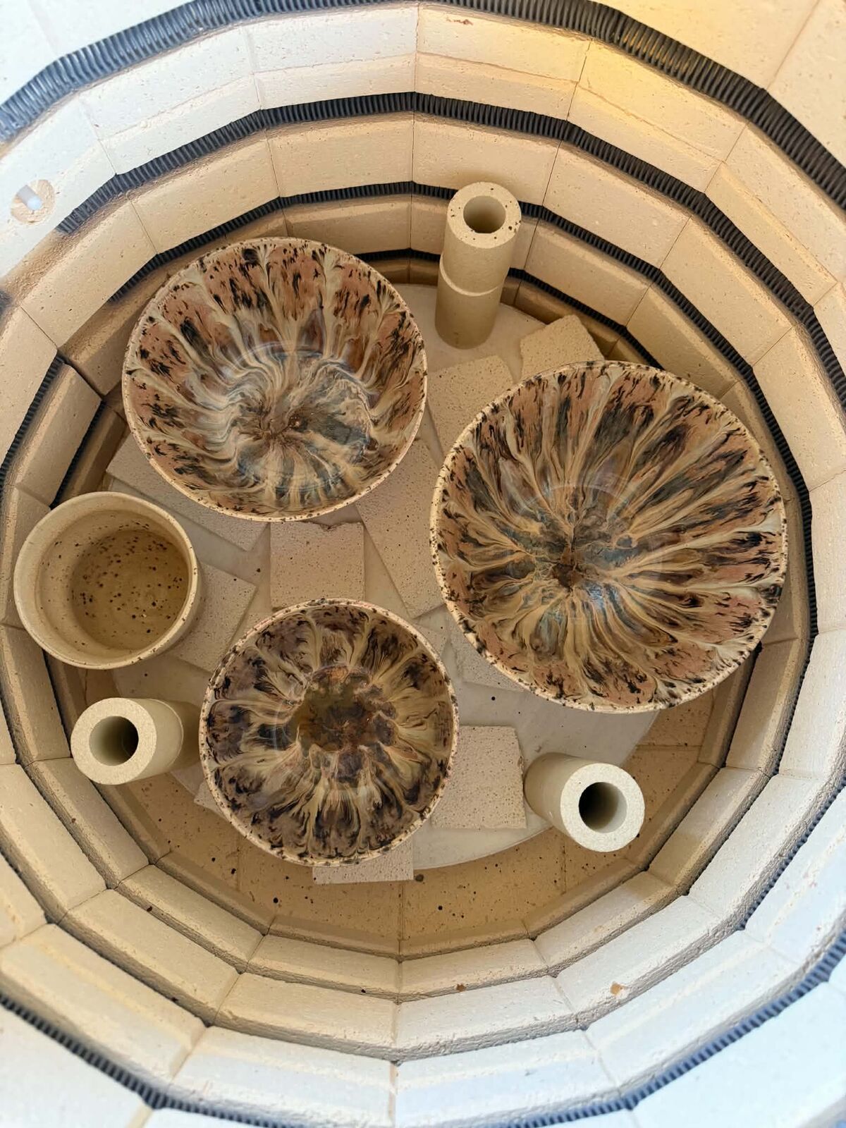 Tre skåle med blomstrende glasur i ovnen, set fra oven