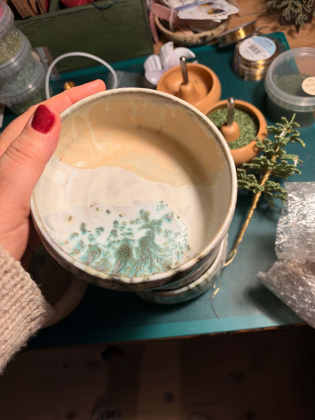 En hånd holder en skål med lys glasur og et grønt, glitrende felt i bunden